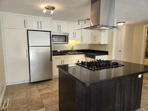 Kitchen featuring white cabinetry, light tile flooring, island range hood, and stainless steel appliances