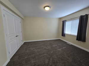 Unfurnished bedroom featuring dark carpet and a closet