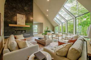 Living room featuring high vaulted ceiling, hardwood floors, and a premium fireplace