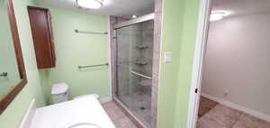 Bathroom featuring tile floors, a shower with door, toilet, and vanity