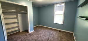 Unfurnished bedroom with carpet and a closet with shelving