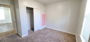 Unfurnished bedroom with carpet flooring and a closet and built in drawers