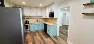 Kitchen featuring white cabinetry, sink, SS appliances, and hardwood / wood-style flooring