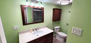 Bathroom featuring vanity with extensive cabinet space, tile flooring, and toilet