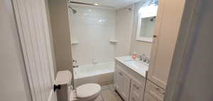 Full bathroom with tile floors, vanity, toilet, and tiled shower / bath combo