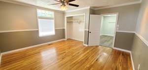 Unfurnished bedroom featuring a textured ceiling, ornamental molding, light wood flooring, and ceiling fan