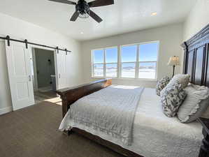 Master bedroom with carpet, a barn door, ceiling fan, and a textured ceiling