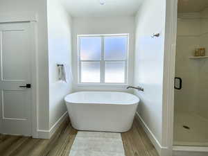 Master bathroom featuring plenty of natural light, shower with separate bathtub, and hardwood / wood-style flooring