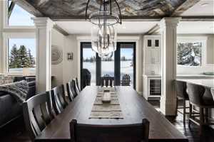 Dining space featuring a chandelier, dark hardwood / wood-style floors, ornate columns, and wine cooler