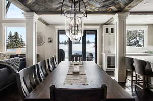 Dining space featuring a chandelier, dark hardwood / wood-style floors, ornate columns, and wine cooler