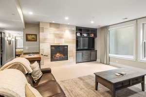 Living room featuring a fireplace, light colored carpet, and tile walls