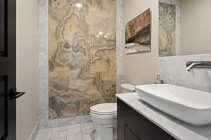 Bathroom with a shower, toilet, tile floors, and large vanity