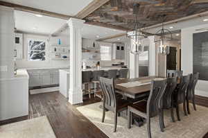 Dining space featuring a healthy amount of sunlight, ornate columns, and dark wood-type flooring