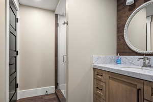 Bathroom featuring a shower with door, hardwood / wood-style floors, and vanity