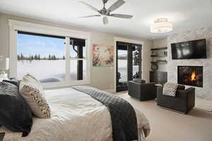 Bedroom featuring carpet flooring, a tiled fireplace, multiple windows, and access to exterior