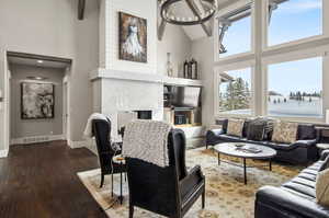 Living room featuring high vaulted ceiling, a wealth of natural light, a high end fireplace, and dark wood-type flooring