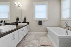 Bathroom featuring a healthy amount of sunlight, tile flooring, vanity with extensive cabinet space, and dual sinks