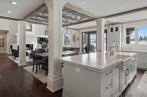 Kitchen with a high end fireplace, a center island with sink, dark hardwood / wood-style flooring, and white cabinetry