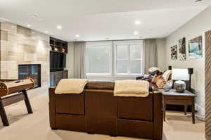 Bedroom with light carpet, a multi sided fireplace, and tile walls