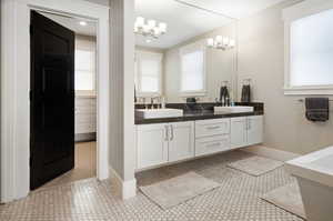 Bathroom featuring a notable chandelier, tile flooring, oversized vanity, and double sink