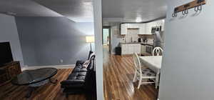 Kitchen featuring backsplash, appliances with stainless steel finishes, white cabinetry, and dark hardwood / wood-style floors