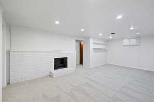 Unfurnished living room with carpet floors and a brick fireplace