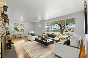 Living room with a stone fireplace, a healthy amount of sunlight, and wood-type flooring