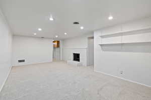 Unfurnished living room with a fireplace and light colored carpet