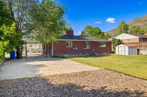 Back of property featuring a yard, a carport, a mountain view, and a shed