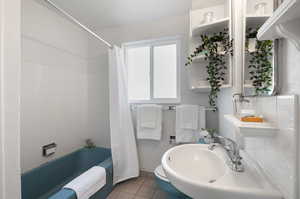 Full bathroom with tile flooring, tasteful backsplash, sink, shower / bath combination with curtain, and toilet