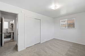 Unfurnished bedroom with carpet, sink, a closet, and ensuite bath