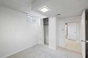 Basement with a textured ceiling and light carpet