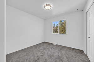 Unfurnished bedroom with dark carpet and a closet