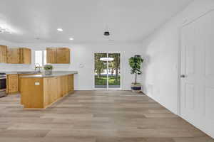 Kitchen featuring light hardwood / wood-style floors, kitchen peninsula, stainless steel range oven, hanging light fixtures, and sink