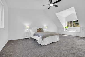 Carpeted bedroom with ceiling fan and vaulted ceiling