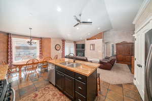 Kitchen featuring a center island with sink, sink, a wealth of natural light, and ceiling fan with notable chandelier