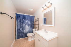 Bathroom featuring tile flooring, toilet, and large vanity