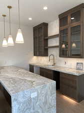 Kitchen featuring sink, light stone countertops, decorative backsplash, and hanging light fixtures