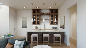 Bar with light stone countertops, sink, light hardwood / wood-style floors, and decorative light fixtures