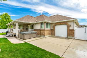 Back of property with a hot tub, a garage, and a yard