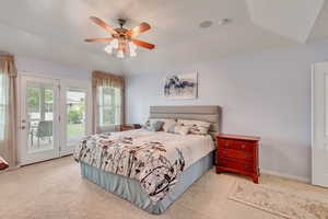 Master bedroom with carpet flooring, ceiling fan, vaulted ceiling, and access to exterior