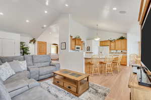 Living room with high vaulted ceiling and light hardwood / wood-style floors