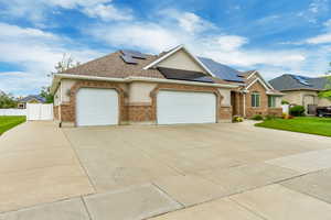 Ranch-style house with a front lawn, a garage, and solar panels