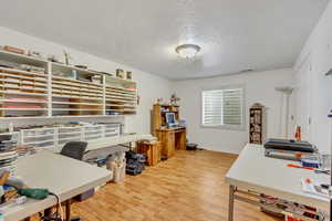 Home office with light hardwood / wood-style floors and a textured ceiling