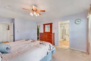 Bedroom with ceiling fan, a closet, carpet floors, ensuite bathroom, and a walk in closet