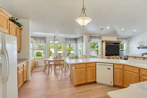 Kitchen with decorative light fixtures, light brown cabinets, light hardwood / wood-style floors, sink, and white appliances