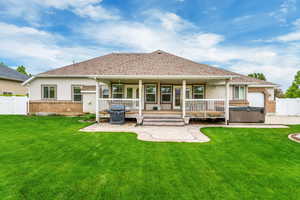 Back of house featuring a yard, a hot tub, and a patio