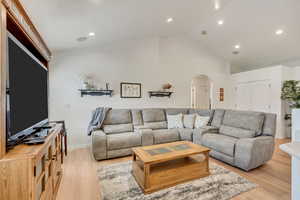 Living room with high vaulted ceiling and light hardwood / wood-style flooring