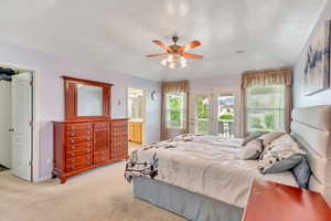 Master bedroom with light colored carpet, vaulted ceiling, connected bathroom, and French doors to the back yard