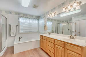 Bathroom with hardwood / wood-style flooring, separate shower and tub, and double sink vanity